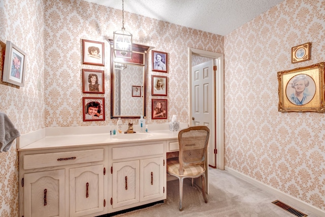 bathroom featuring visible vents, a textured ceiling, vanity, baseboards, and wallpapered walls