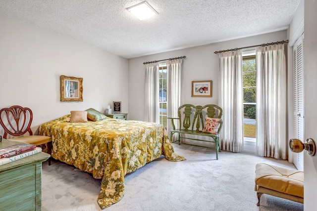 bedroom with a textured ceiling, carpet floors, and multiple windows