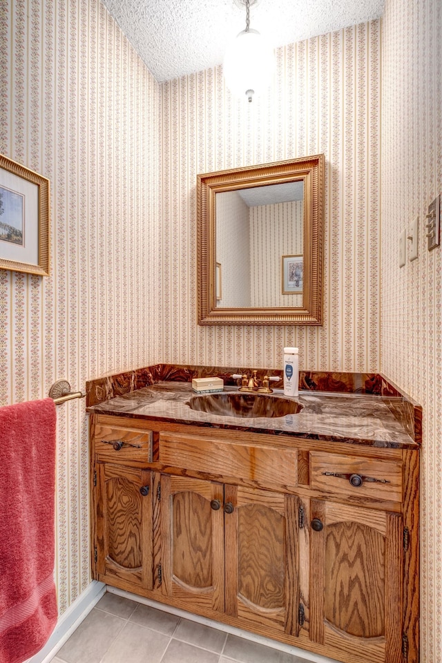 bathroom featuring wallpapered walls, tile patterned flooring, a textured ceiling, and vanity