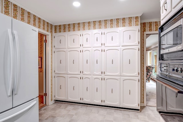 kitchen featuring stainless steel microwave, freestanding refrigerator, white cabinetry, black oven, and wallpapered walls