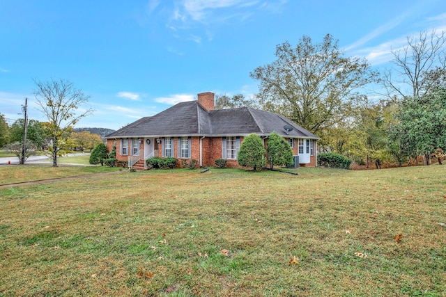 view of front of property featuring brick siding, a chimney, and a front yard