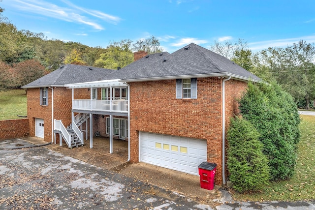 back of house featuring an attached garage, brick siding, concrete driveway, roof with shingles, and a chimney