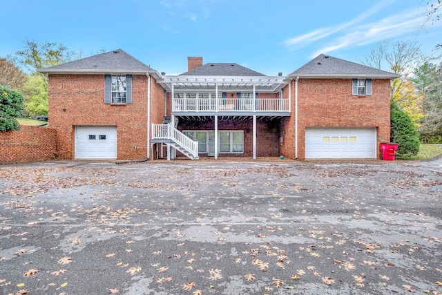 rear view of property featuring brick siding, an attached garage, and a pergola