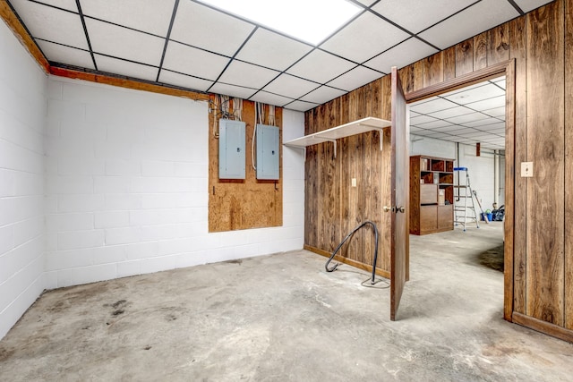 spare room featuring concrete flooring, electric panel, and concrete block wall