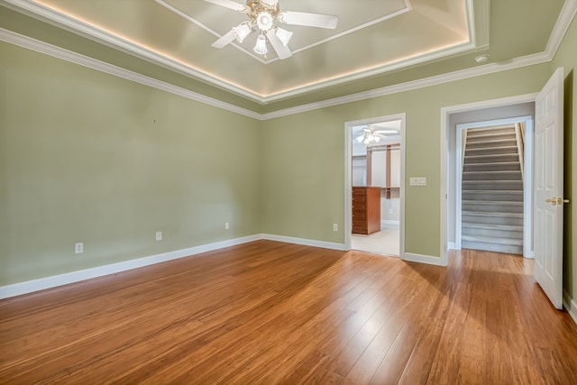 unfurnished room with ornamental molding, light hardwood / wood-style floors, ceiling fan, and a raised ceiling