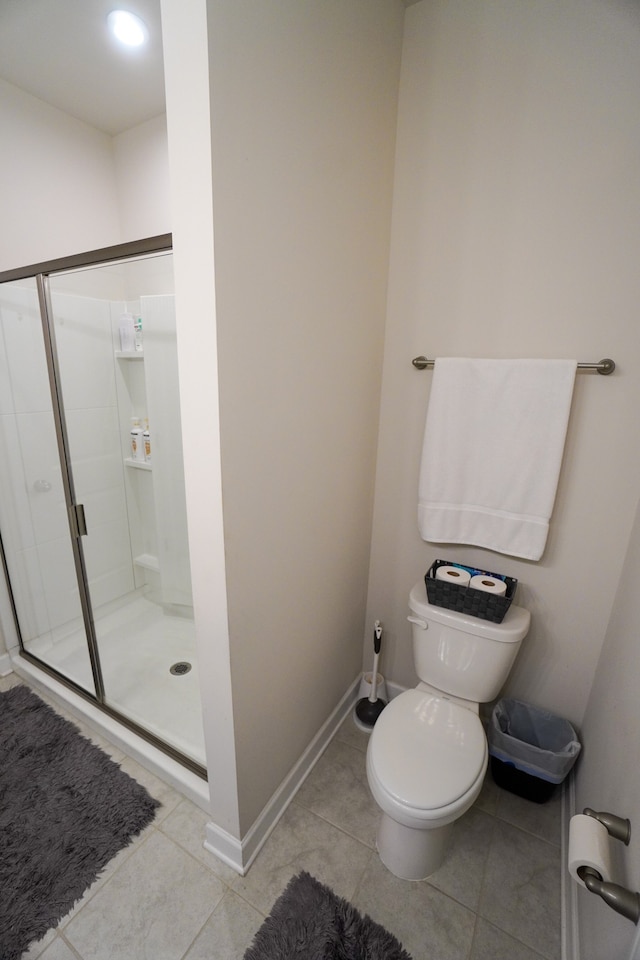 bathroom with toilet, tile patterned floors, and a shower with shower door