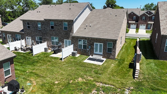 rear view of house with central AC and a lawn