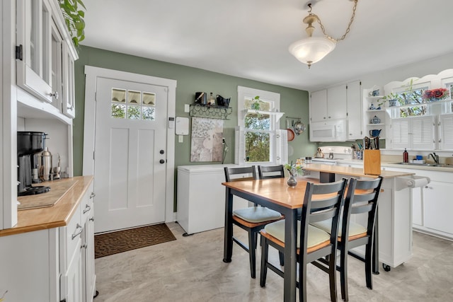 kitchen featuring a wealth of natural light, butcher block countertops, white appliances, and white cabinets