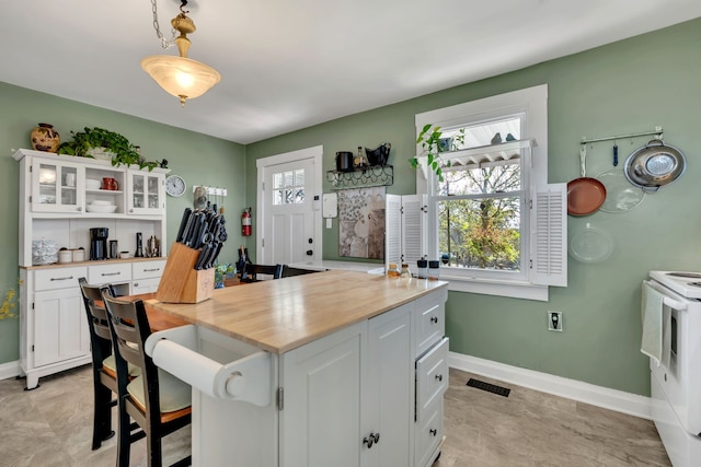 kitchen featuring hanging light fixtures, wood counters, white range with electric cooktop, and white cabinets