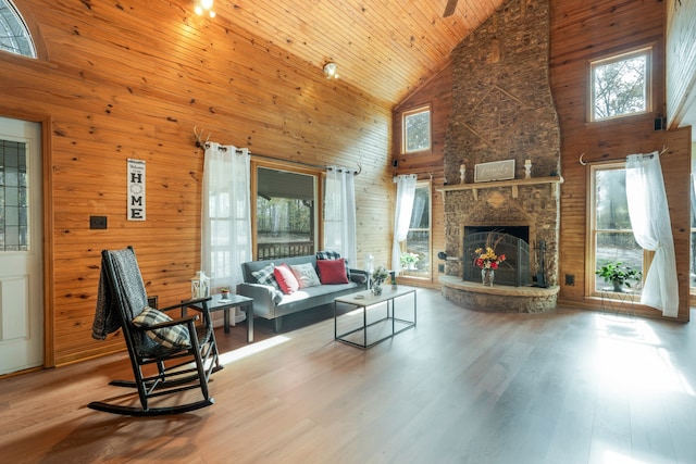 living room with wood ceiling, wood walls, hardwood / wood-style flooring, high vaulted ceiling, and a fireplace