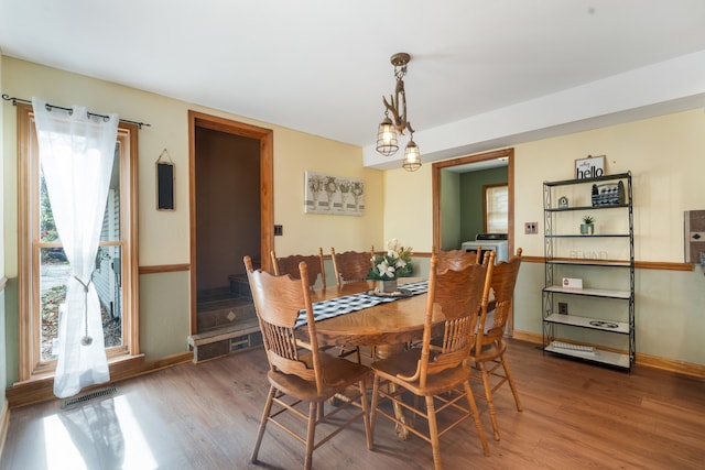 dining area featuring wood-type flooring and a notable chandelier