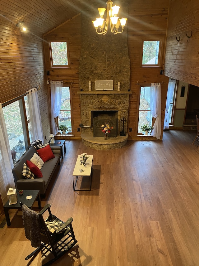 living room featuring hardwood / wood-style flooring, high vaulted ceiling, a stone fireplace, wood ceiling, and a chandelier