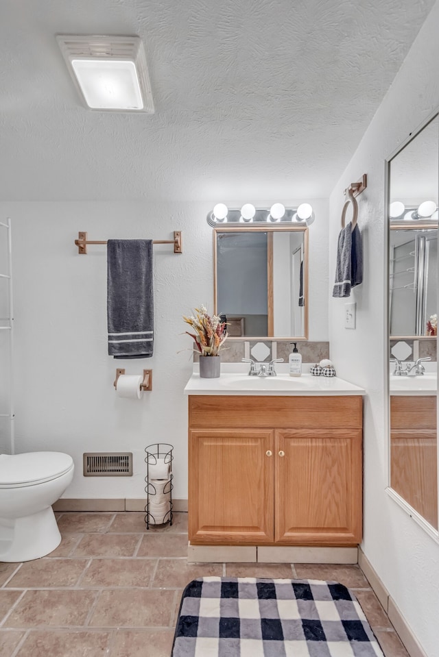 bathroom with toilet, vanity, a textured ceiling, and tile patterned floors