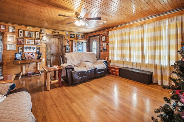 living room featuring light wood-type flooring, wooden walls, ceiling fan, and wooden ceiling