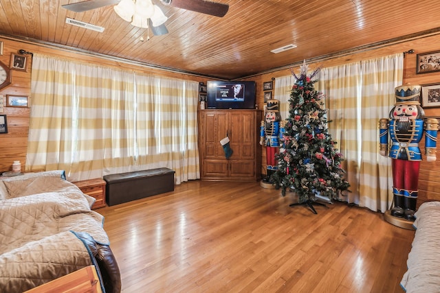 living room with hardwood / wood-style floors, wooden walls, ceiling fan, and wooden ceiling