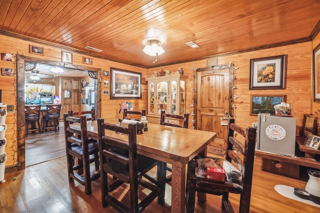 dining room featuring wooden walls, wood-type flooring, and wooden ceiling