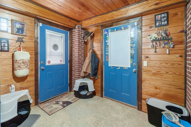 foyer entrance with wooden walls, wood ceiling, and carpet floors