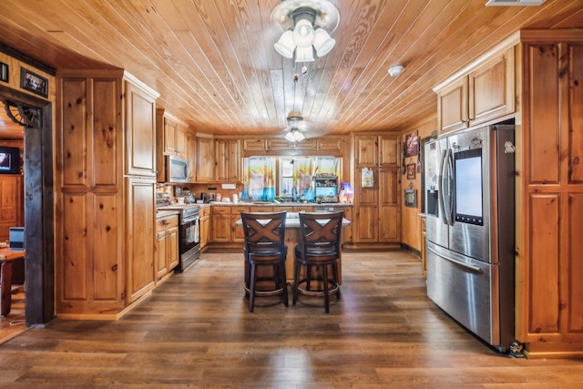 kitchen featuring dark hardwood / wood-style floors, a breakfast bar area, appliances with stainless steel finishes, and a center island