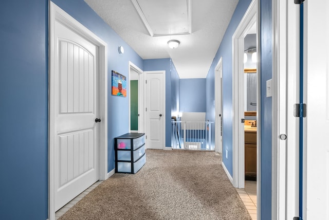 hallway with light carpet and a textured ceiling