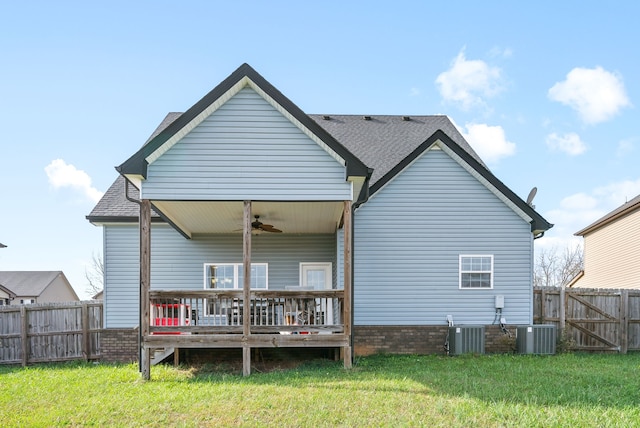 rear view of property featuring central air condition unit, a wooden deck, ceiling fan, and a lawn