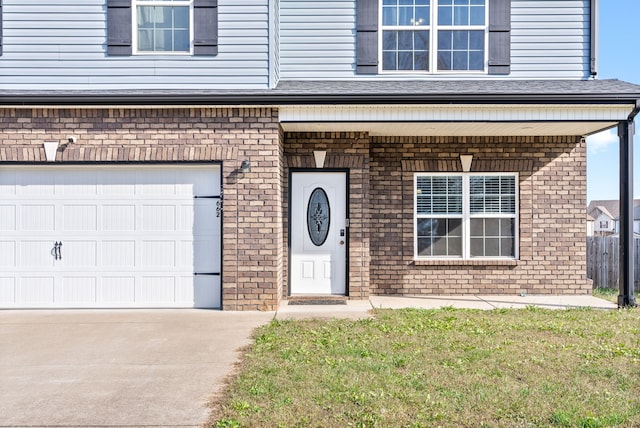 view of exterior entry with a yard and a garage