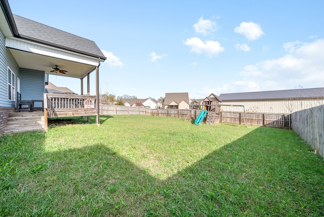 view of yard featuring a playground, ceiling fan, and a deck