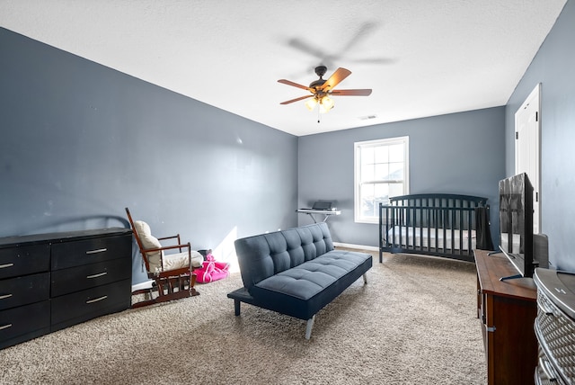 bedroom with carpet flooring, a crib, and ceiling fan