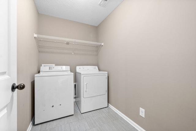 clothes washing area featuring washer and clothes dryer and a textured ceiling