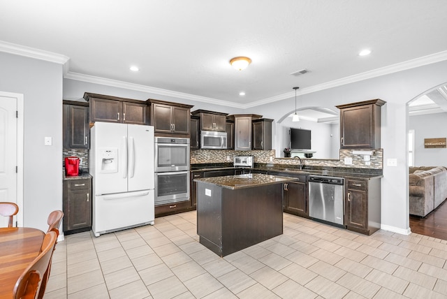 kitchen featuring a center island, backsplash, stainless steel appliances, and ornamental molding