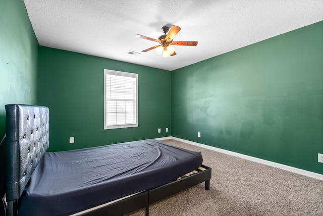 carpeted bedroom with ceiling fan and a textured ceiling