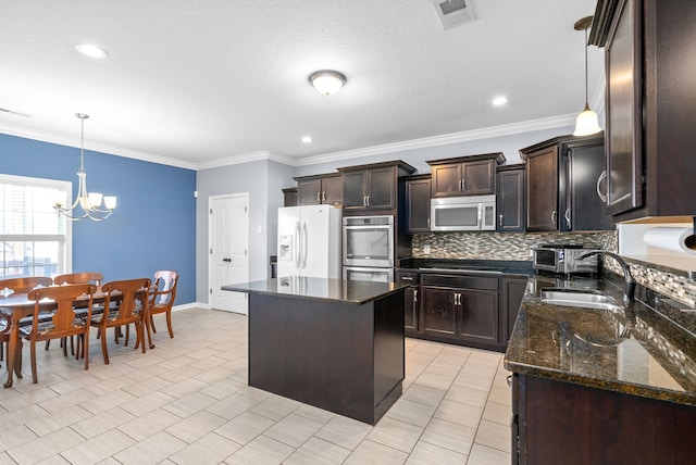 kitchen with a kitchen island, hanging light fixtures, appliances with stainless steel finishes, and a chandelier