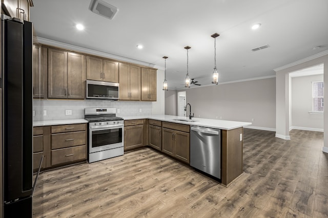 kitchen featuring appliances with stainless steel finishes, dark hardwood / wood-style flooring, pendant lighting, sink, and kitchen peninsula