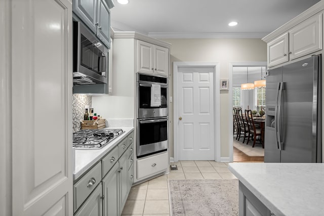 kitchen featuring stainless steel appliances, decorative backsplash, light tile patterned floors, gray cabinetry, and ornamental molding