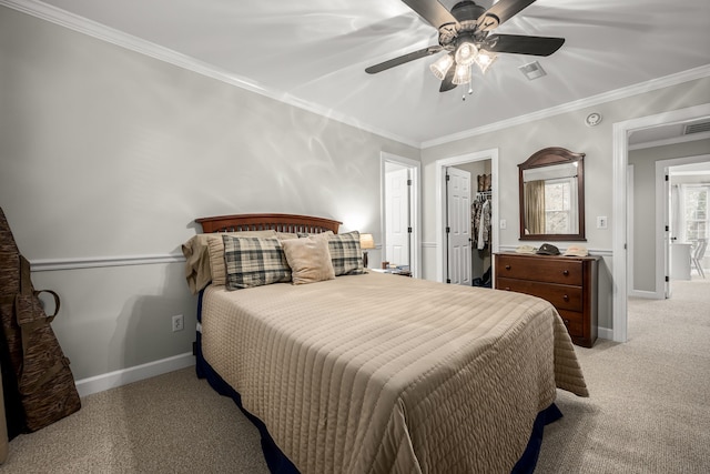 carpeted bedroom with ceiling fan, crown molding, and a walk in closet