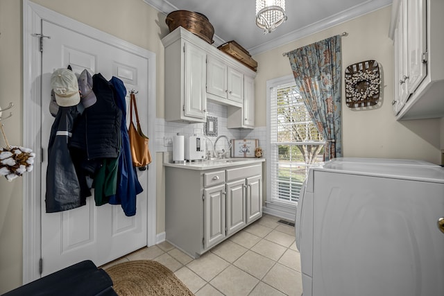 laundry area featuring light tile patterned flooring, ornamental molding, washer / clothes dryer, cabinets, and sink