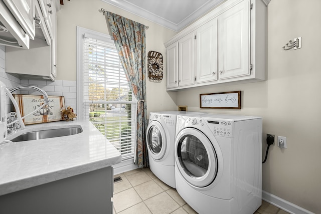 laundry room featuring washing machine and dryer, cabinets, sink, and ornamental molding