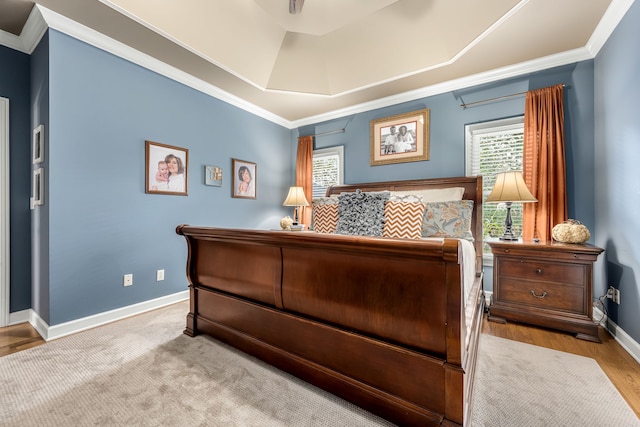 bedroom with a raised ceiling, ornamental molding, and light hardwood / wood-style flooring