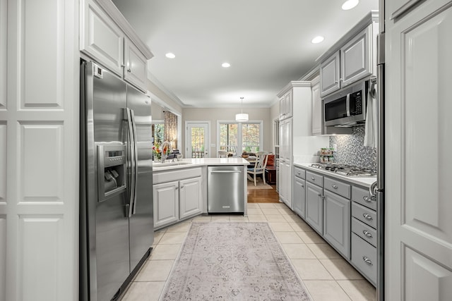 kitchen featuring stainless steel appliances, gray cabinets, sink, and ornamental molding