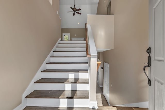 stairway with tile patterned floors, ceiling fan, and a towering ceiling