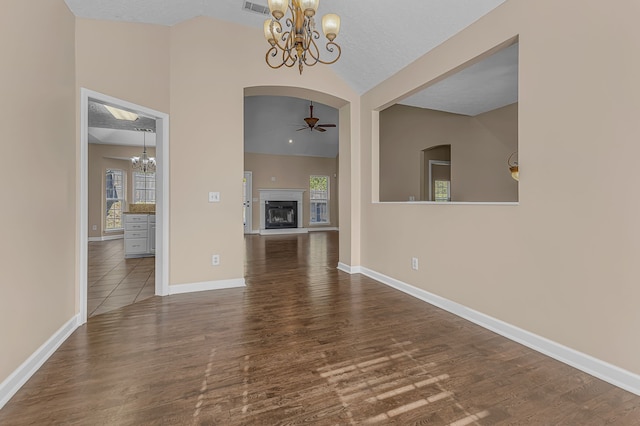 interior space with a textured ceiling, ceiling fan with notable chandelier, lofted ceiling, and dark hardwood / wood-style floors