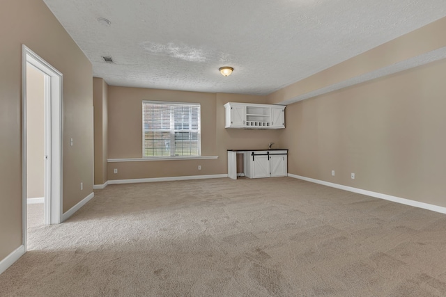 carpeted empty room with a textured ceiling