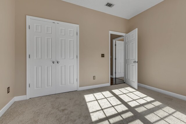 unfurnished bedroom featuring light carpet and a closet