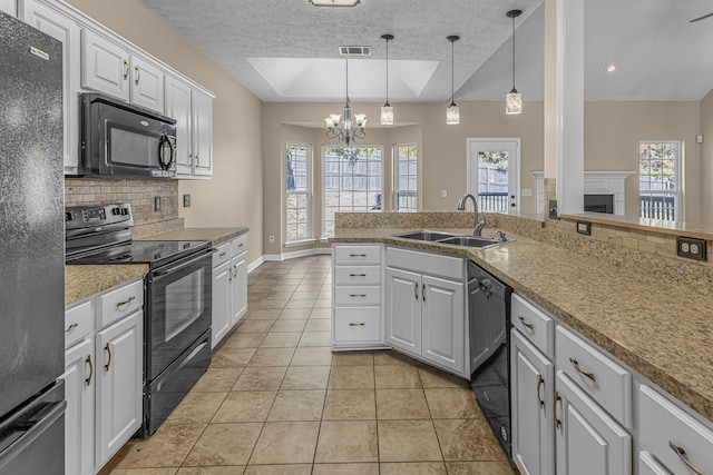 kitchen with hanging light fixtures, a wealth of natural light, white cabinetry, and black appliances