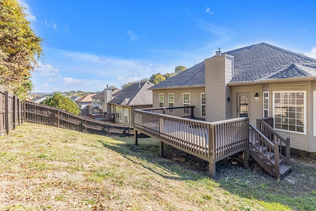 rear view of property with a wooden deck and a lawn