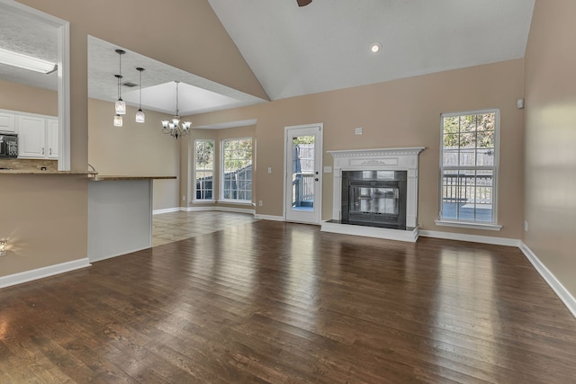 unfurnished living room featuring dark hardwood / wood-style flooring, vaulted ceiling, and plenty of natural light