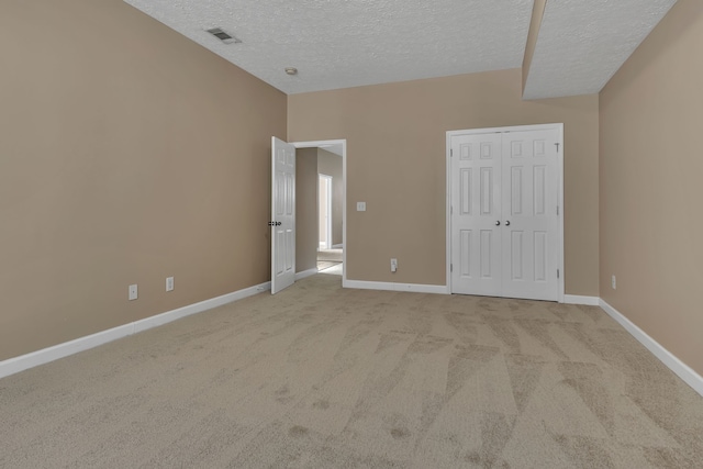 unfurnished bedroom with light carpet, a textured ceiling, and a closet