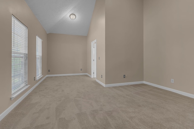 carpeted spare room with a textured ceiling and high vaulted ceiling