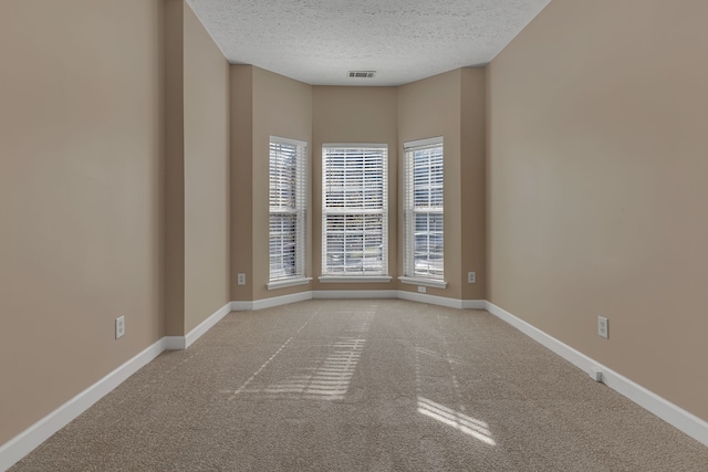 carpeted empty room featuring a textured ceiling