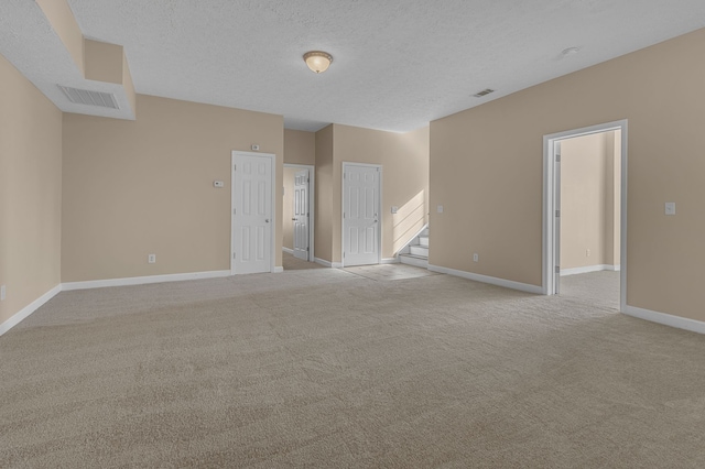 unfurnished room with a textured ceiling and light colored carpet