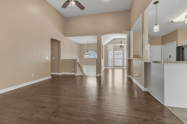 unfurnished living room with ceiling fan, a textured ceiling, dark hardwood / wood-style flooring, and high vaulted ceiling